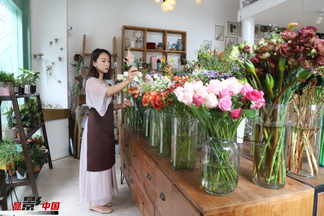 王黎媛是一名河南姑娘，在昆明念完大學后，就再也舍不下春城的藍天陽光、青山碧水，更舍不下這里的四時繁花，于是就干脆留了下來，成了一名媒體人。2017年的時候又毅然辭去工作，創(chuàng)業(yè)開起了花店，成了都市里的一名“花房姑娘”。圖為王黎媛在自己的花店中整理鮮花。新華網 周亞平/攝 念新洪/文